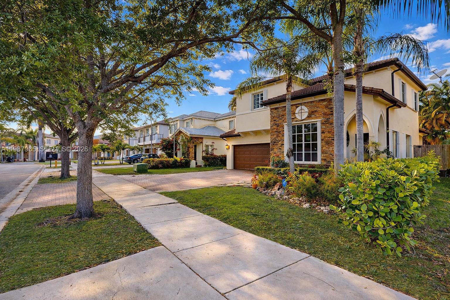 A two-story suburban house with a stone facade, brown garage door, and a paved driveway — 16479 SW 50th Ter, Miami FL 33185, MIAMI, FL