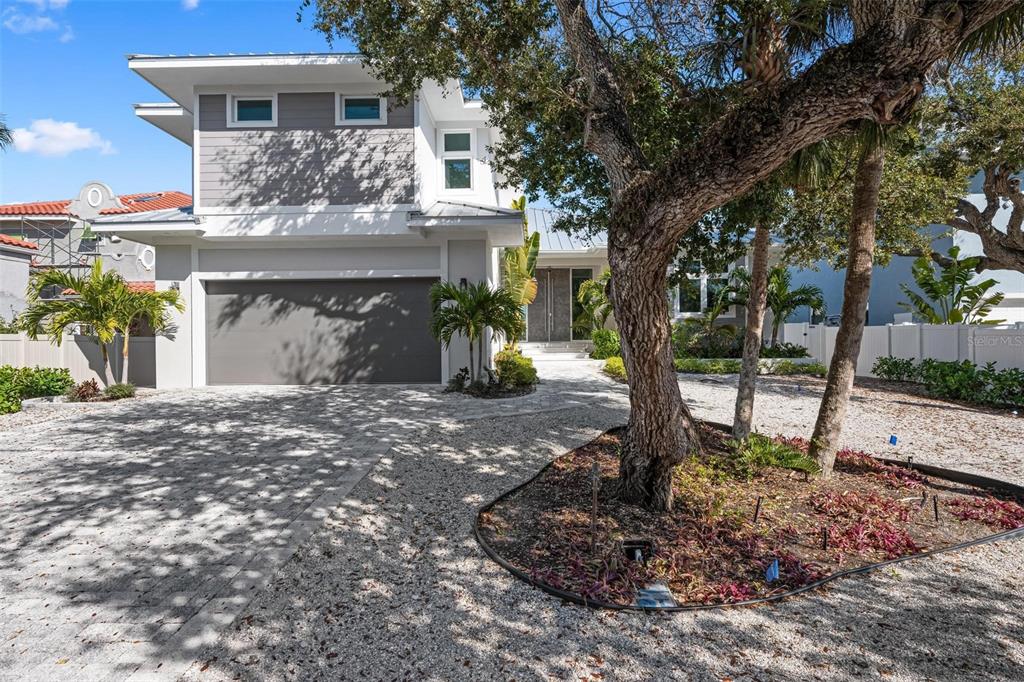 A modern two-story house features a gray garage, a paved driveway, and a landscaped front yard — 4819 HIGEL AVENUE, SARASOTA, FL
