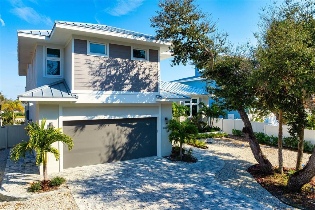 A two-story house with a gray garage door, metal roof, and a paved driveway — 4819 HIGEL AVENUE, SARASOTA, FL
