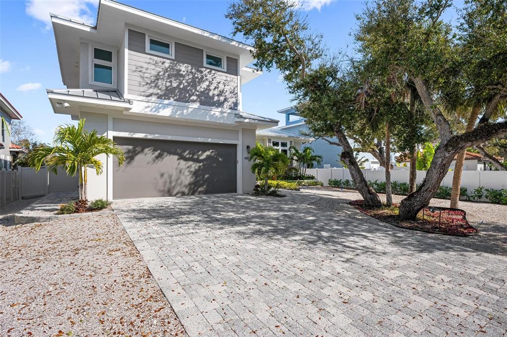 A two-story house with a gray garage, paved driveway, and mature trees in the yard — 4819 HIGEL AVENUE, SARASOTA, FL
