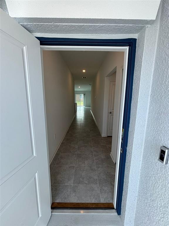 A view through an open doorway into a long hallway with gray tile flooring — 655 DARING DRIVE, DAVENPORT, FL