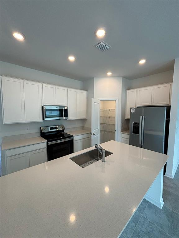 A kitchen features white cabinets, stainless steel appliances, a center island, and a walk-in pantry — 655 DARING DRIVE, DAVENPORT, FL