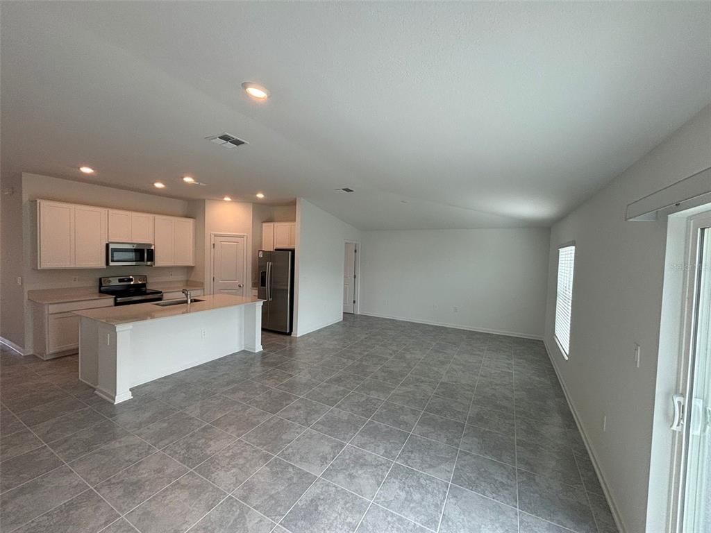 An open-concept kitchen and living area with white cabinets, a center island, and tiled floors — 655 DARING DRIVE, DAVENPORT, FL