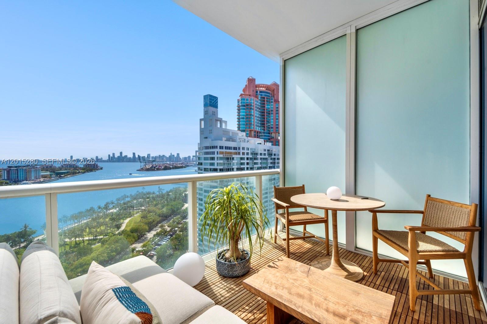 A balcony with wooden decking, outdoor furniture, and a panoramic view of the city skyline — 100 S Pointe Dr # 2003, Miami Beach FL 33139, MIAMI BEACH, FL