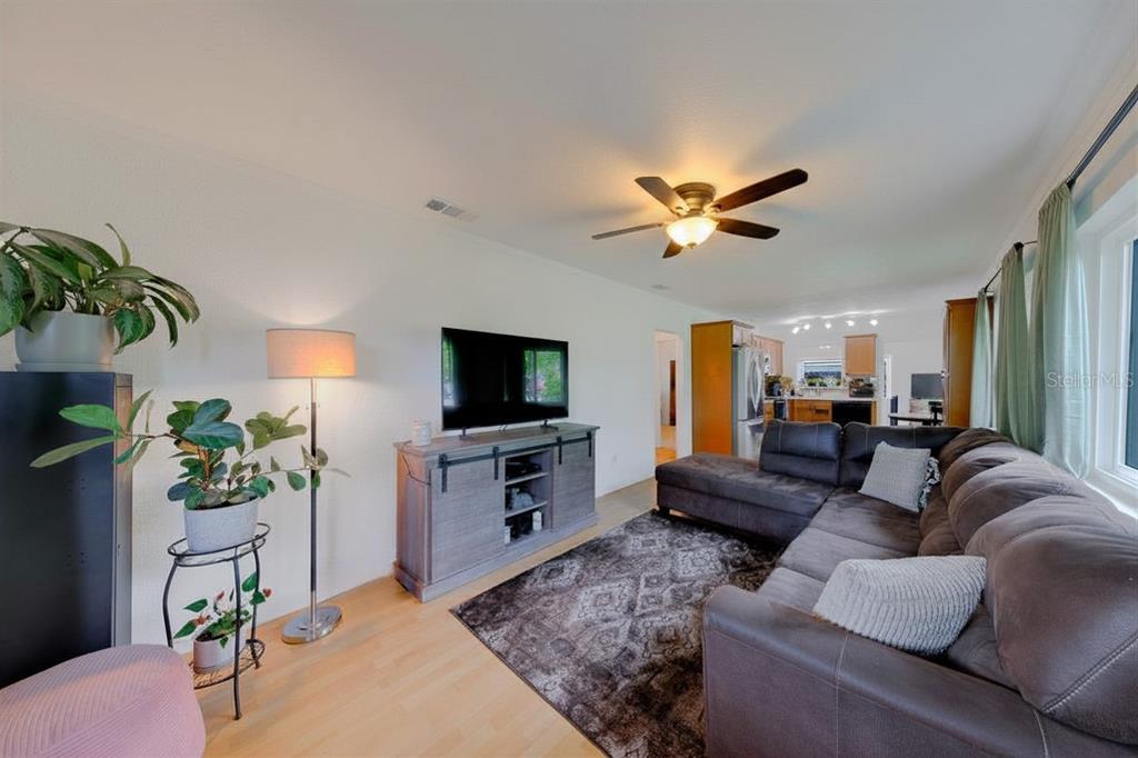 A living room features a sectional sofa, a television on a console, and a ceiling fan — 2773 BELLE HAVEN DRIVE, CLEARWATER, FL
