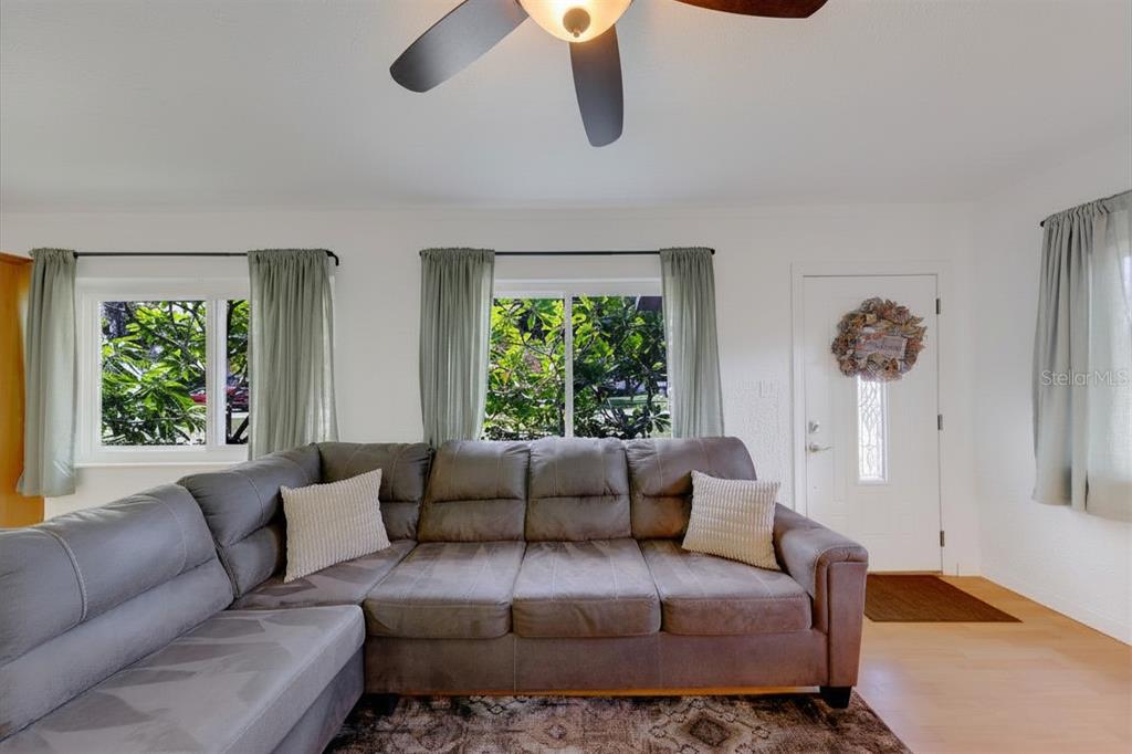 A living room features a grey sectional sofa, two windows with green curtains, and a door — 2773 BELLE HAVEN DRIVE, CLEARWATER, FL