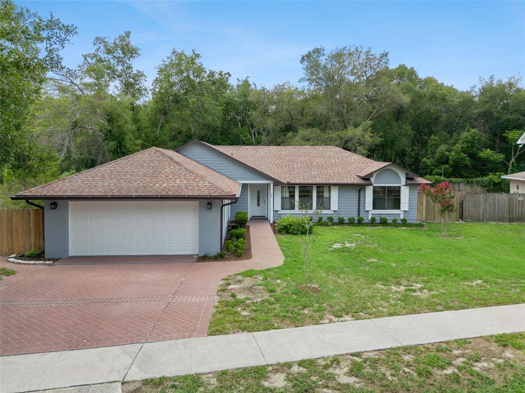 A single-story house with a blue exterior, a two-car garage, and a brick driveway — 125 DONNA CIRCLE, SANFORD, FL