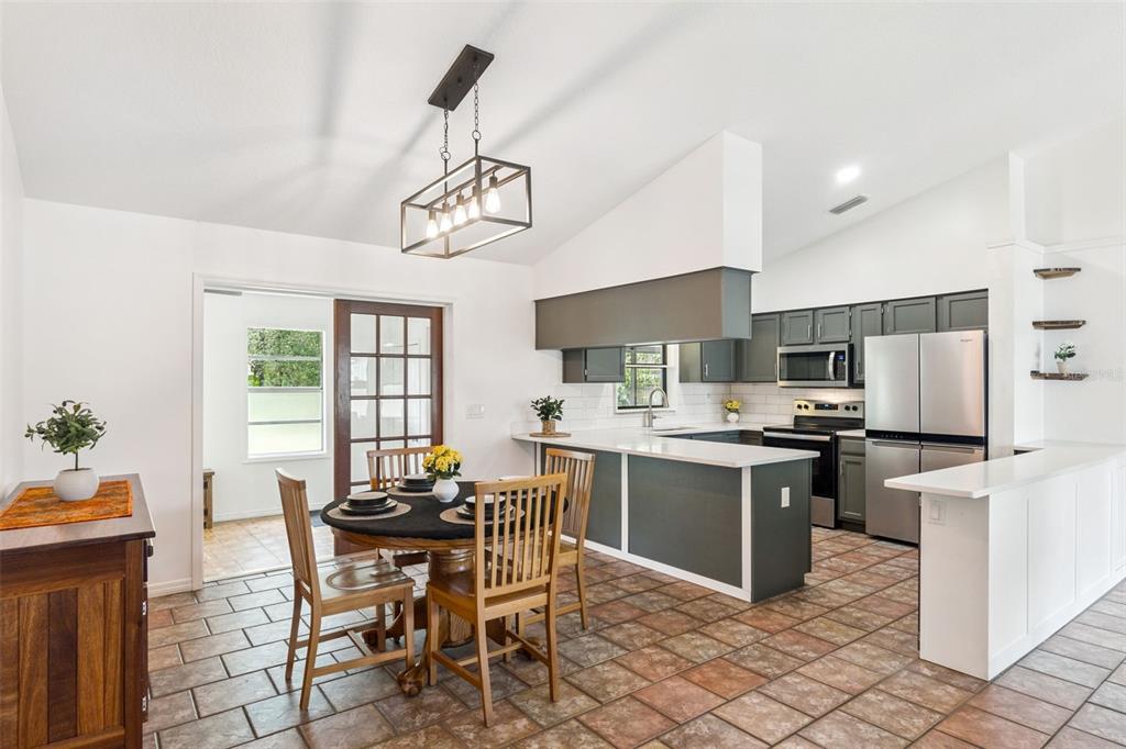 A kitchen and dining area featuring tile floors, dark cabinetry, and a rectangular pendant light — 125 DONNA CIRCLE, SANFORD, FL