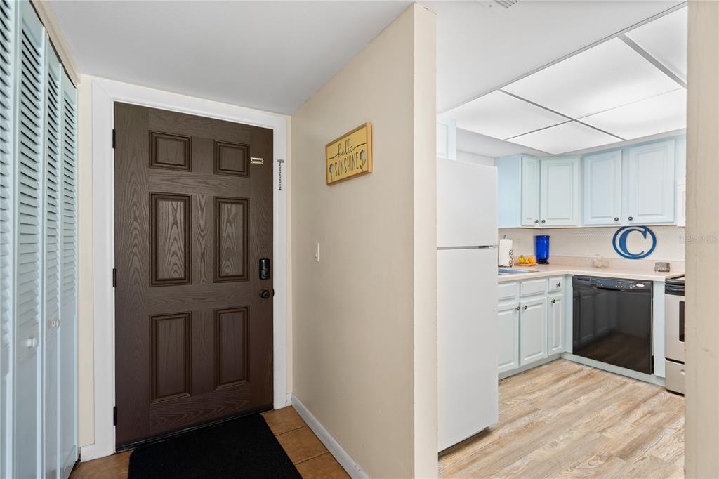 An entryway with a dark wood door leads into a kitchen with light blue cabinets — 2100 OCEAN SHORE BOULEVARD UNIT 1150, ORMOND BEACH, FL