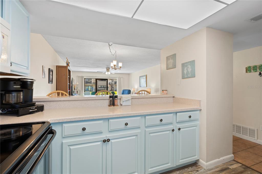 A kitchen with light blue cabinets and a pass-through window overlooking the living area — 2100 OCEAN SHORE BOULEVARD UNIT 1150, ORMOND BEACH, FL