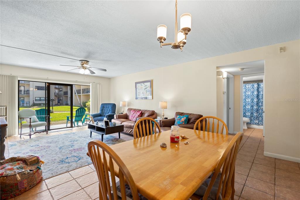 A dining area with a wooden table leads into a living room with sliding glass doors — 2100 OCEAN SHORE BOULEVARD UNIT 1150, ORMOND BEACH, FL