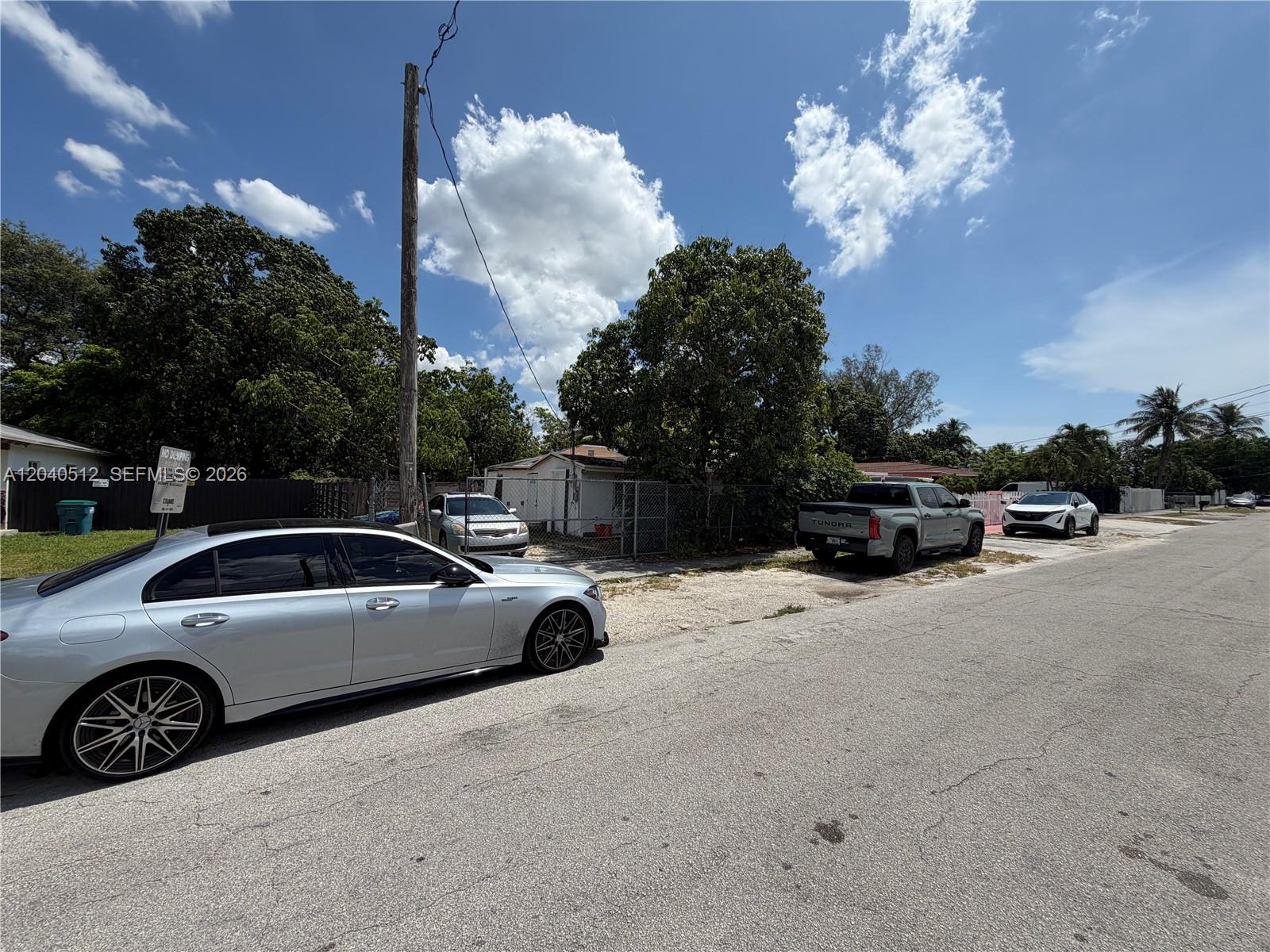 A silver sedan is parked on the street in front of a fenced residential lot — 867 NW 109th St, Miami FL 33168, MIAMI, FL