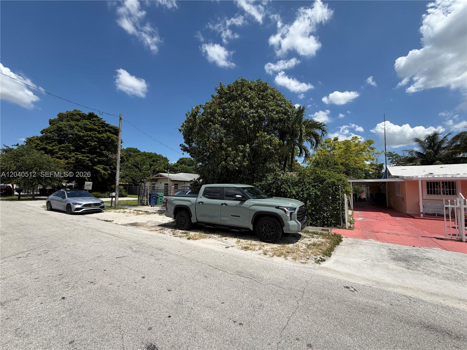 A light green pickup truck is parked on a gravel area beside a residential house — 867 NW 109th St, Miami FL 33168, MIAMI, FL