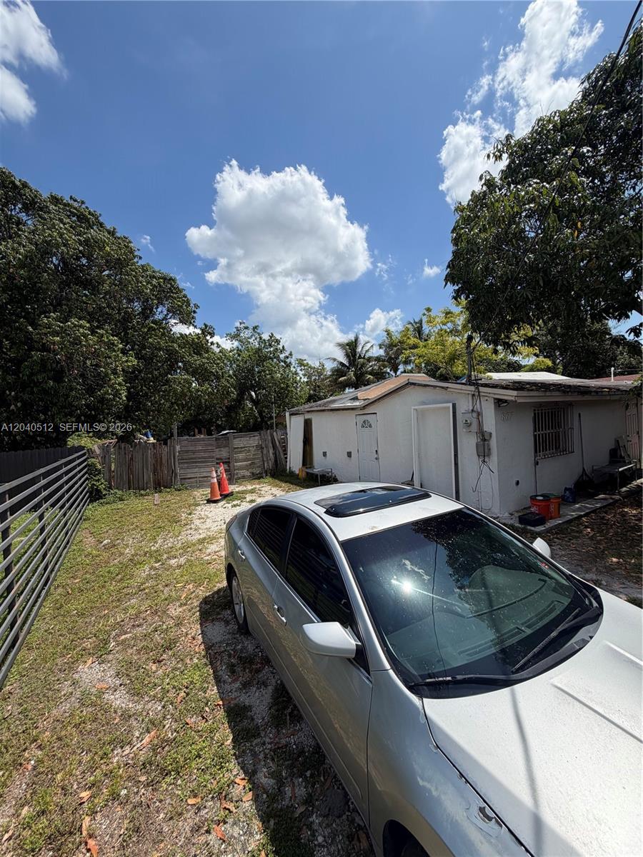 A silver car is parked on a gravel driveway next to a small white building — 867 NW 109th St, Miami FL 33168, MIAMI, FL