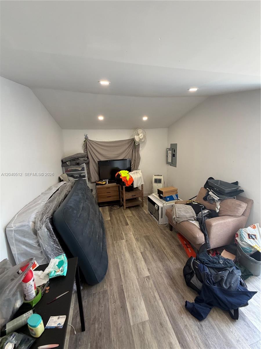 A cluttered room features wood-look flooring, recessed lighting, a television, and various pieces of furniture — 867 NW 109th St, Miami FL 33168, MIAMI, FL