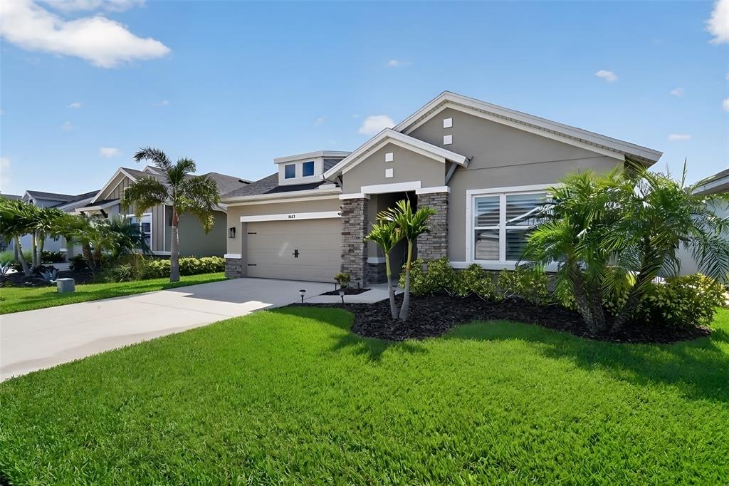 A covered entryway features stone-clad pillars, a light-colored stucco wall, and a glass-paneled front door — 8612 ARROW CREEK DRIVE, PARRISH, FL