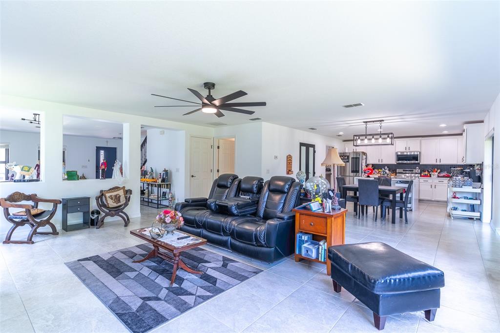 An open-concept living room and kitchen featuring tile flooring, a black leather sofa, and dining area — 2926 BOATING BOULEVARD, KISSIMMEE, FL