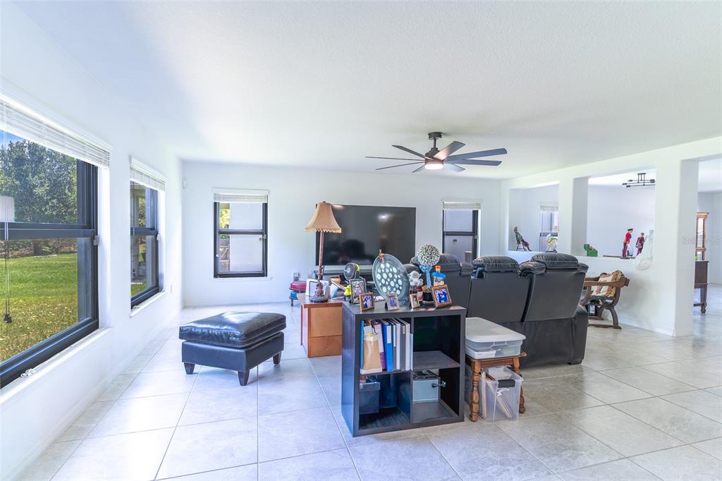 A bright living room features light tile flooring, a black ceiling fan, and large windows — 2926 BOATING BOULEVARD, KISSIMMEE, FL
