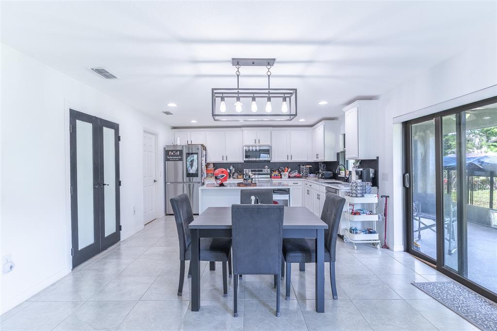 A kitchen and dining area with white cabinets, a central island, and tile flooring — 2926 BOATING BOULEVARD, KISSIMMEE, FL