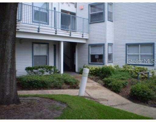 A view of a multi-story apartment building exterior with a balcony and walkway — 2532 WOODGATE BOULEVARD UNIT 205, ORLANDO, FL