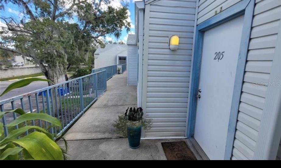 An exterior walkway leads to the entrance of a second-story apartment unit numbered 205 — 2532 WOODGATE BOULEVARD UNIT 205, ORLANDO, FL