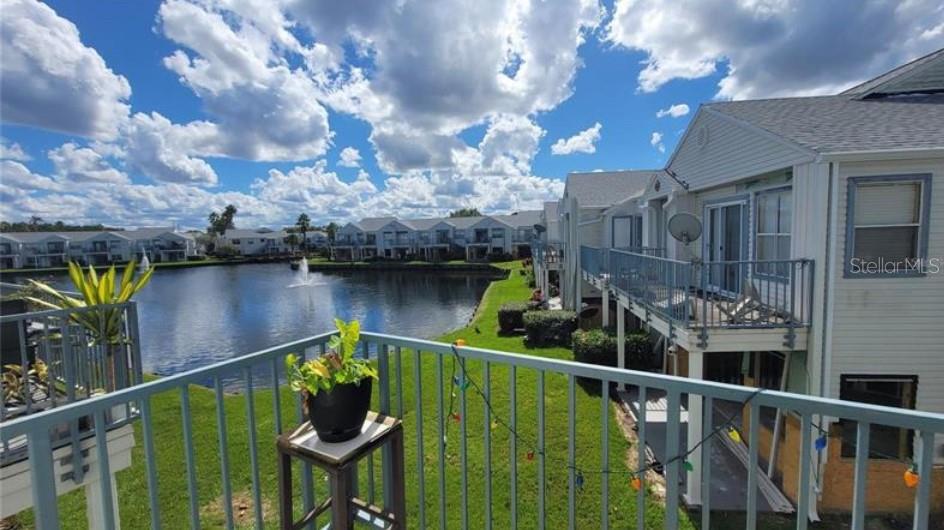 A view from a balcony overlooking a pond and neighboring apartment buildings under a cloudy sky — 2532 WOODGATE BOULEVARD UNIT 205, ORLANDO, FL