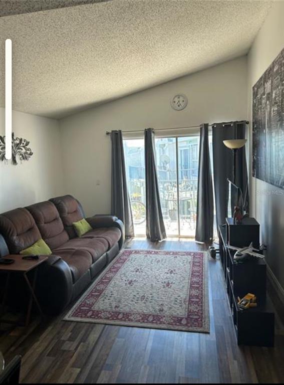 A living room features a brown leather sofa, a patterned area rug, and sliding glass doors — 2532 WOODGATE BOULEVARD UNIT 205, ORLANDO, FL
