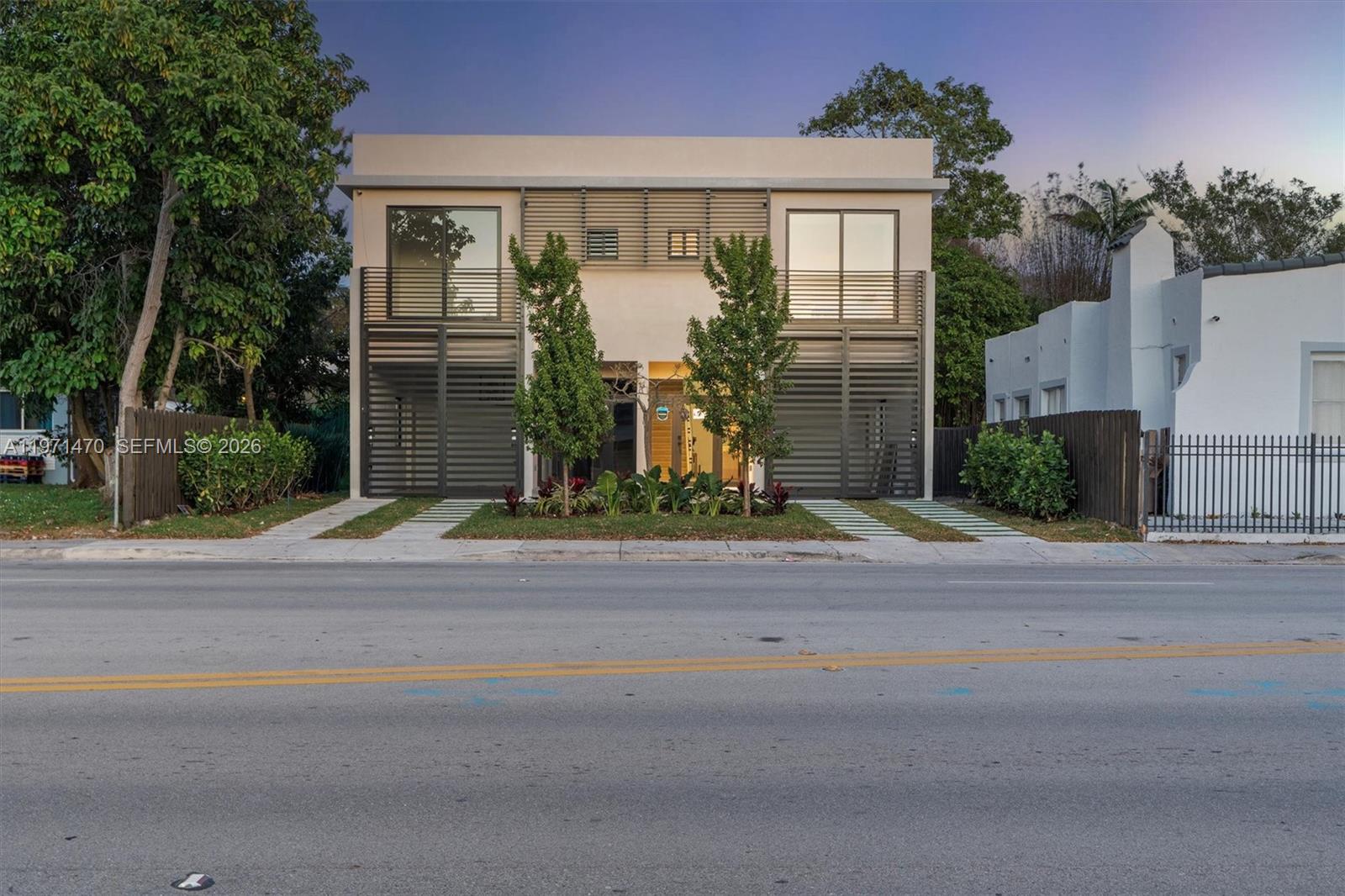 A modern two-story duplex features horizontal slat screens, balconies, and a central landscaped entrance — 4715 N Miami Ave, Miami FL 33127, MIAMI, FL