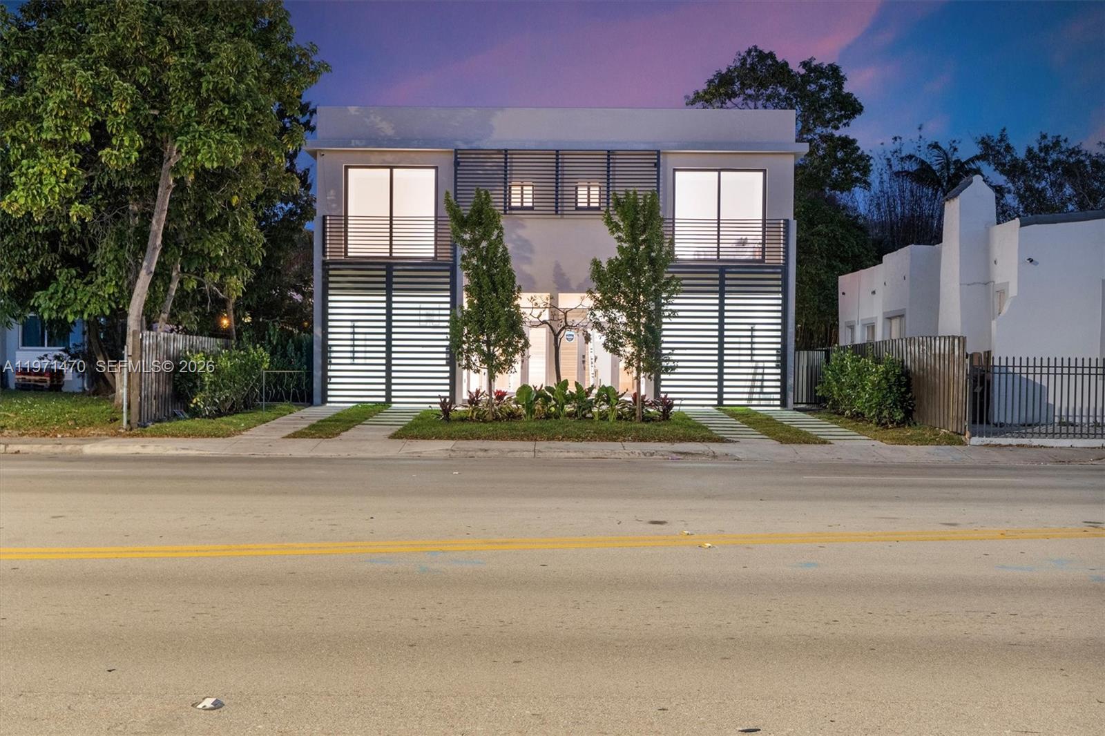 A modern two-story house features horizontal slat screens, balconies, and a central landscaped entrance — 4715 N Miami Ave, Miami FL 33127, MIAMI, FL