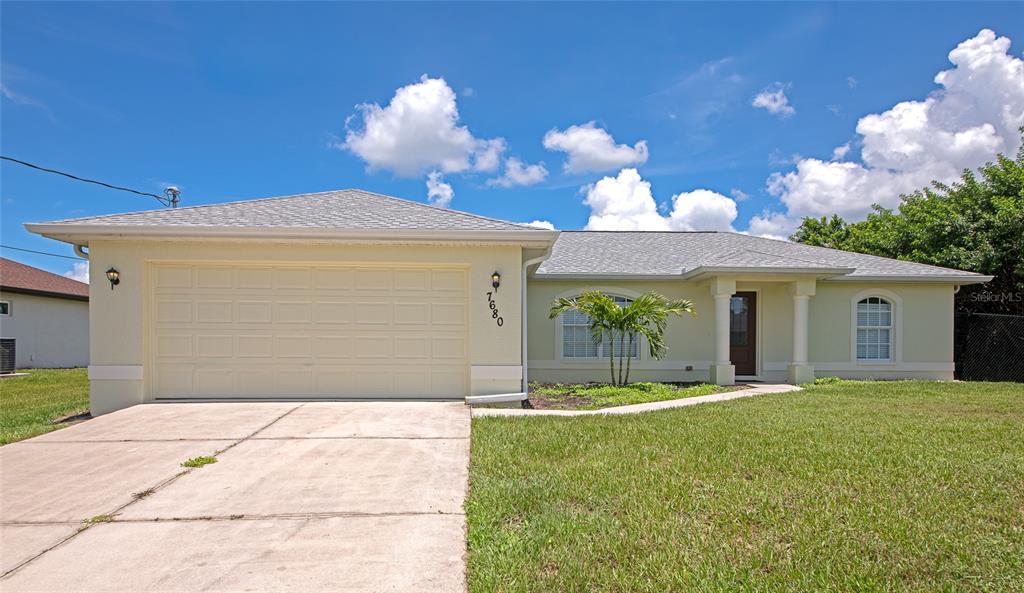A single-story house with a two-car garage, light-colored stucco exterior, and a concrete driveway — 7680 LAMPLIGHTER AVENUE, NORTH PORT, FL