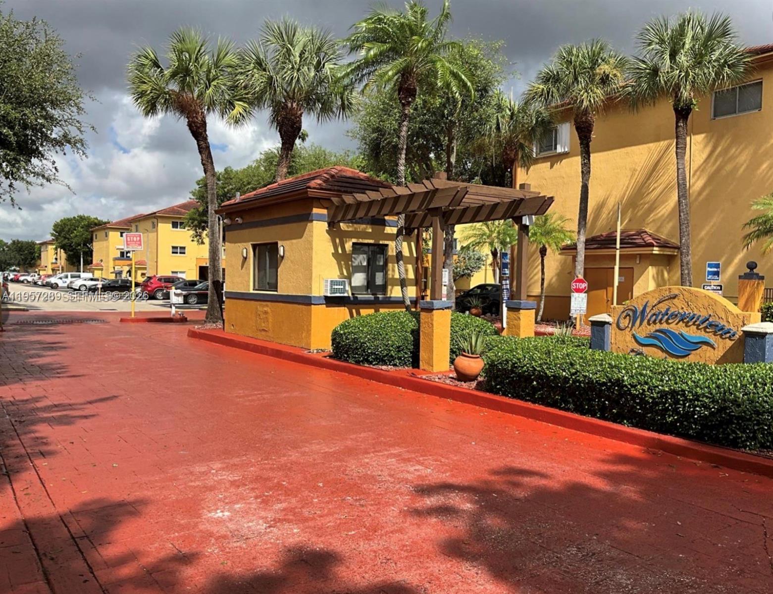A guardhouse stands at the entrance of an apartment complex with palm trees and signage — 8260 SW 149th Ct # 204, Miami FL 33193, MIAMI, FL