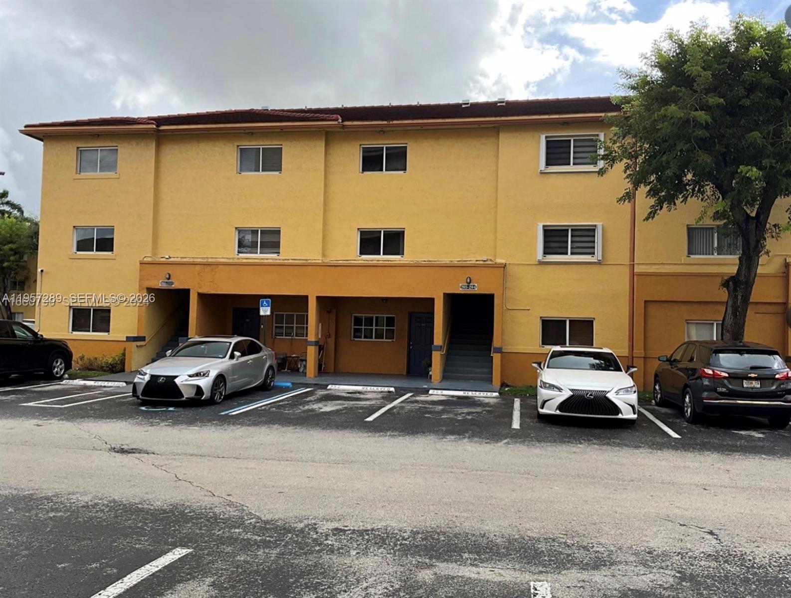 A three-story yellow apartment building with a parking lot in front — 8260 SW 149th Ct # 204, Miami FL 33193, MIAMI, FL