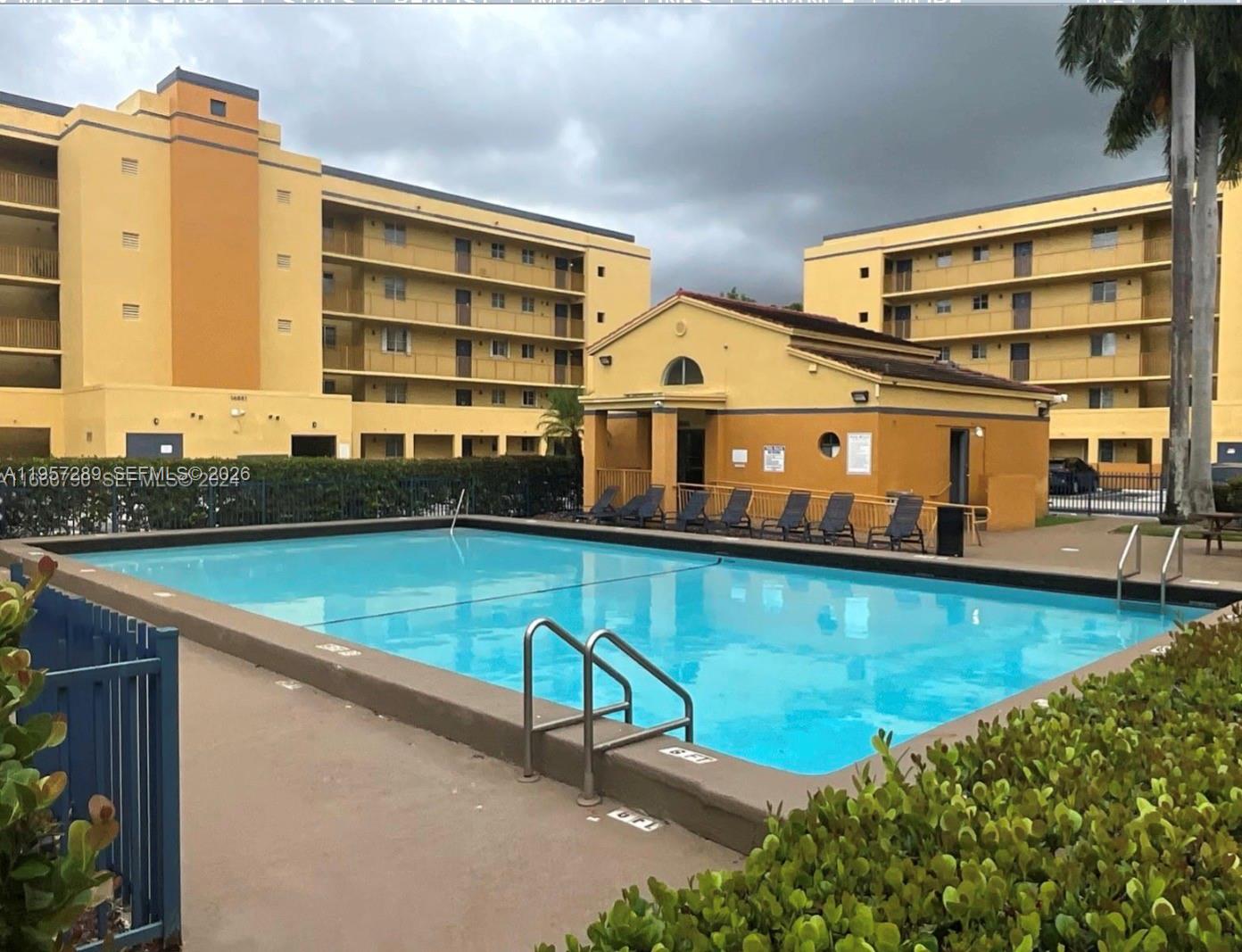 An outdoor swimming pool is situated in front of a multi-story yellow apartment building — 8260 SW 149th Ct # 204, Miami FL 33193, MIAMI, FL