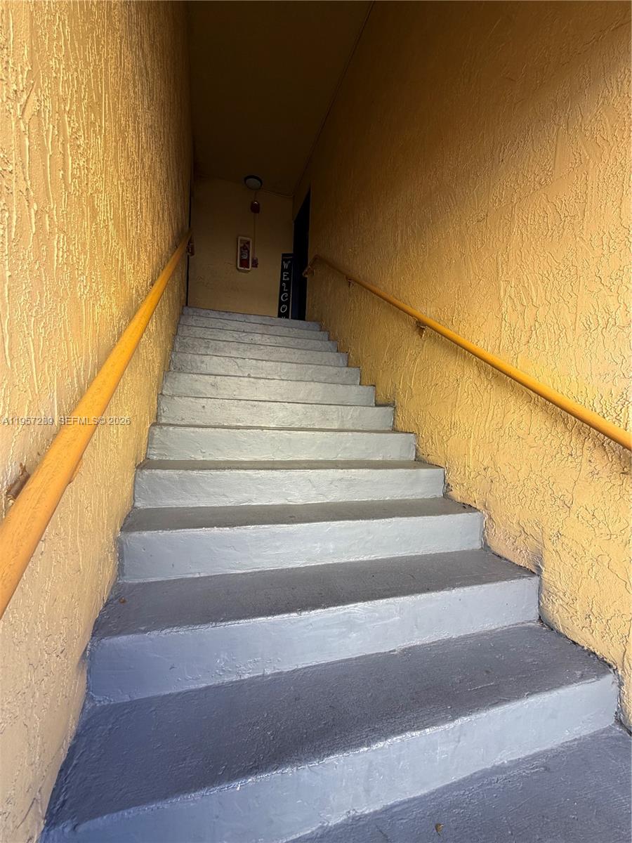 A set of gray concrete stairs leads up between two yellow textured walls — 8260 SW 149th Ct # 204, Miami FL 33193, MIAMI, FL