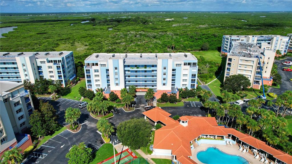 An aerial view shows several multi-story apartment buildings, a swimming pool, and surrounding green landscape — 5300 S ATLANTIC AVENUE UNIT 7-403, NEW SMYRNA BEACH, FL