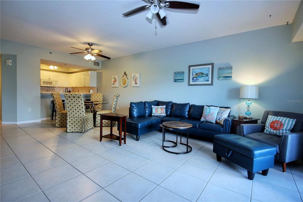 A living room with blue tile floors, a blue sectional sofa, and an open kitchen — 5300 S ATLANTIC AVENUE UNIT 7-403, NEW SMYRNA BEACH, FL