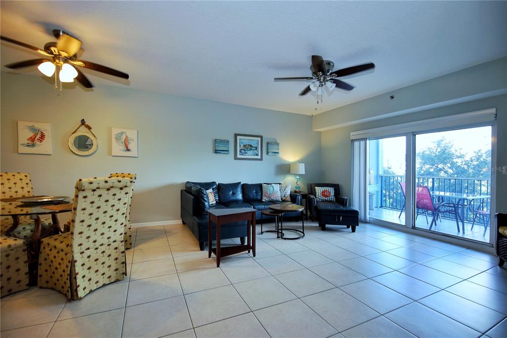 A living and dining area with tile floors, ceiling fans, and a sliding glass door — 5300 S ATLANTIC AVENUE UNIT 7-403, NEW SMYRNA BEACH, FL