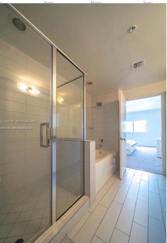 A bathroom features a glass-enclosed shower, a white bathtub, and light-colored tile flooring — 999 SW 1st Ave # 2105, Miami FL 33130, MIAMI, FL