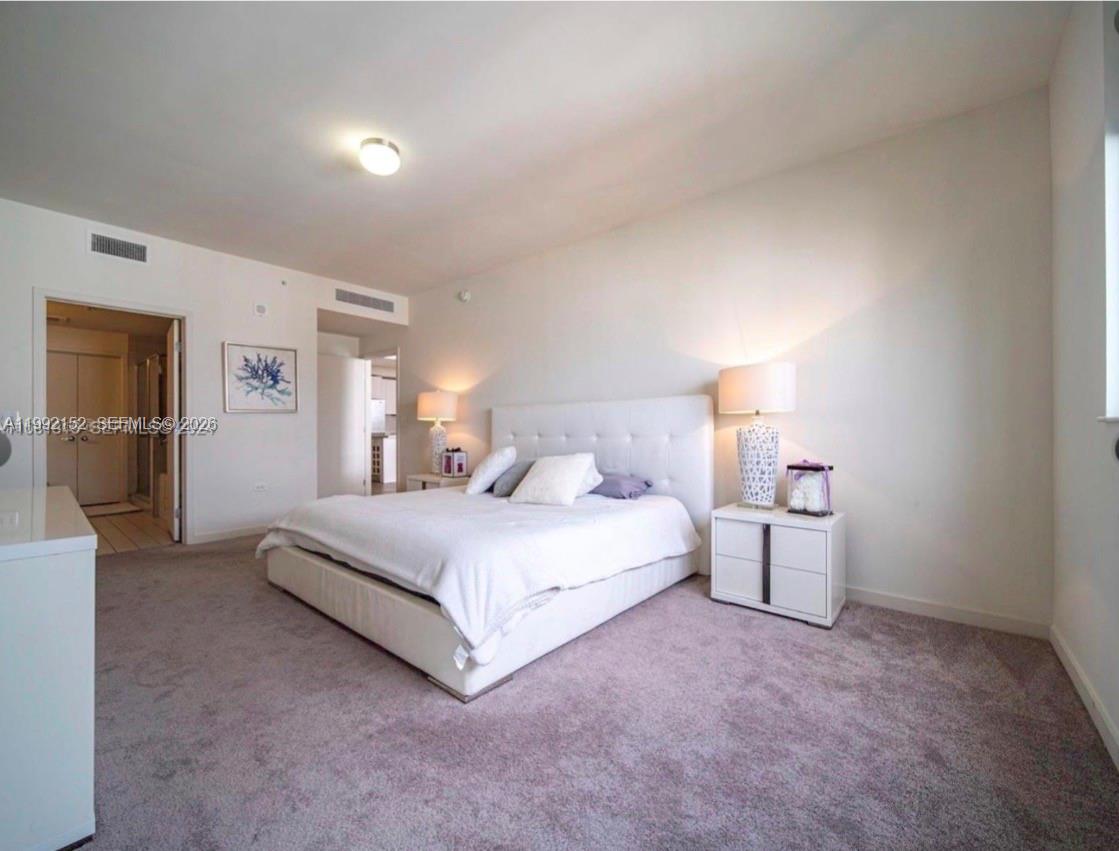 A bedroom features a white upholstered bed, two nightstands with lamps, and gray carpeting — 999 SW 1st Ave # 2105, Miami FL 33130, MIAMI, FL