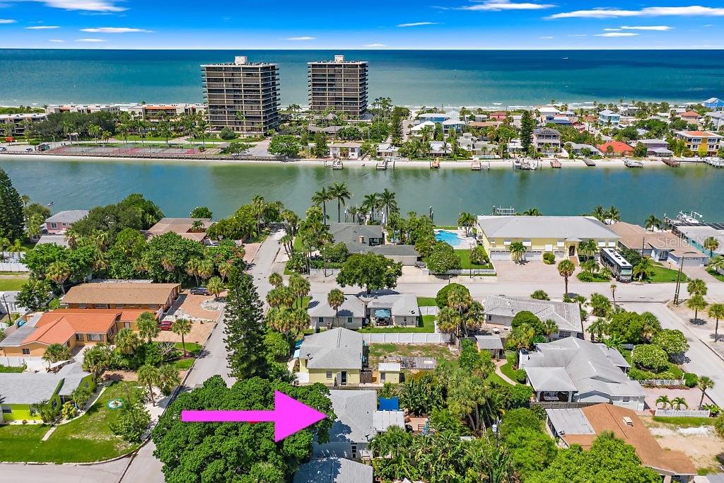 An aerial view shows a residential neighborhood with houses, palm trees, and a nearby beach — 517 79TH AVENUE, ST PETE BEACH, FL