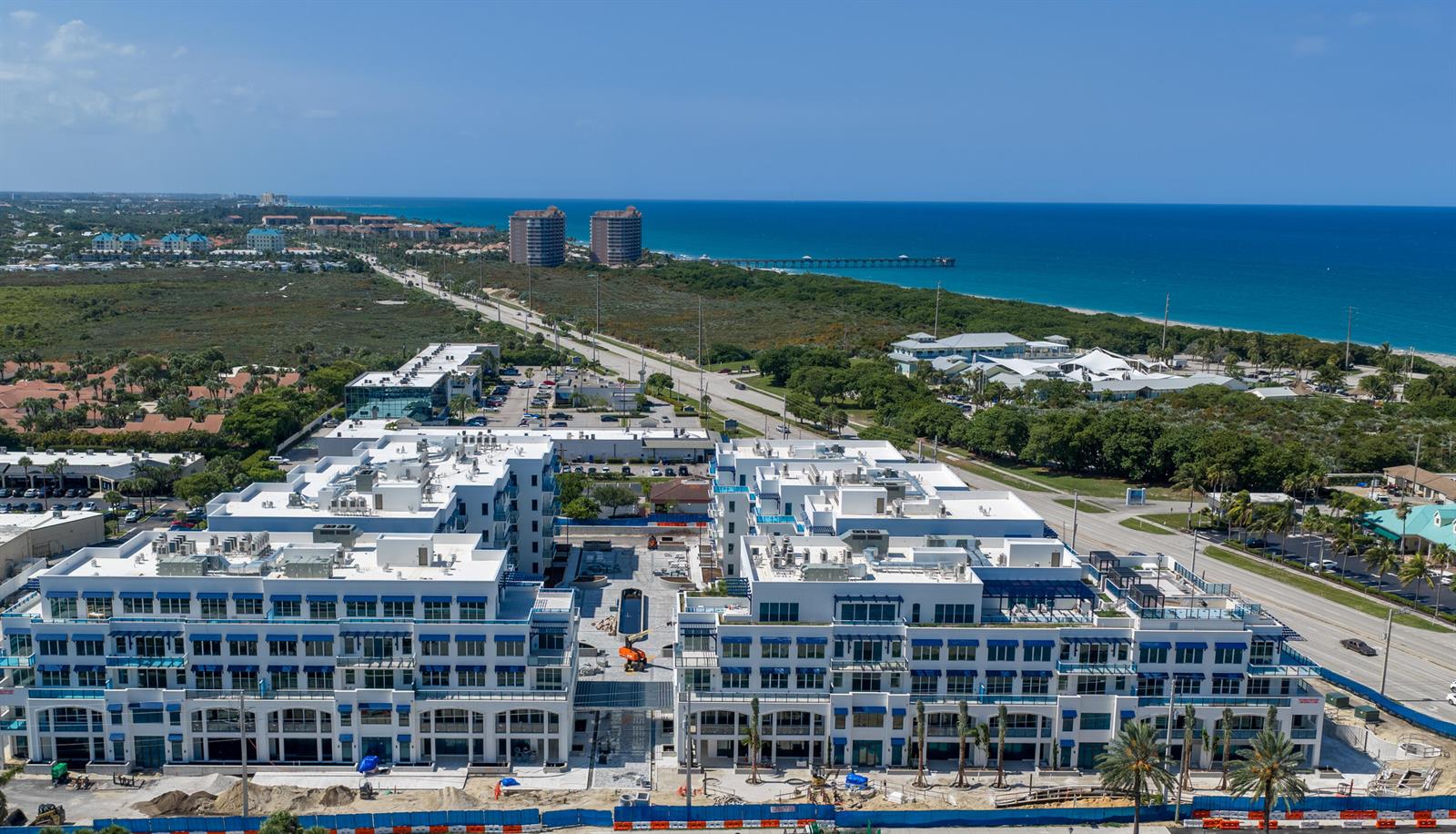An aerial view shows a large, modern white apartment complex under construction near a coastal highway — 1011 U.s. Hwy 1 # D203, Juno Beach FL 33408, JUNO BEACH, FL