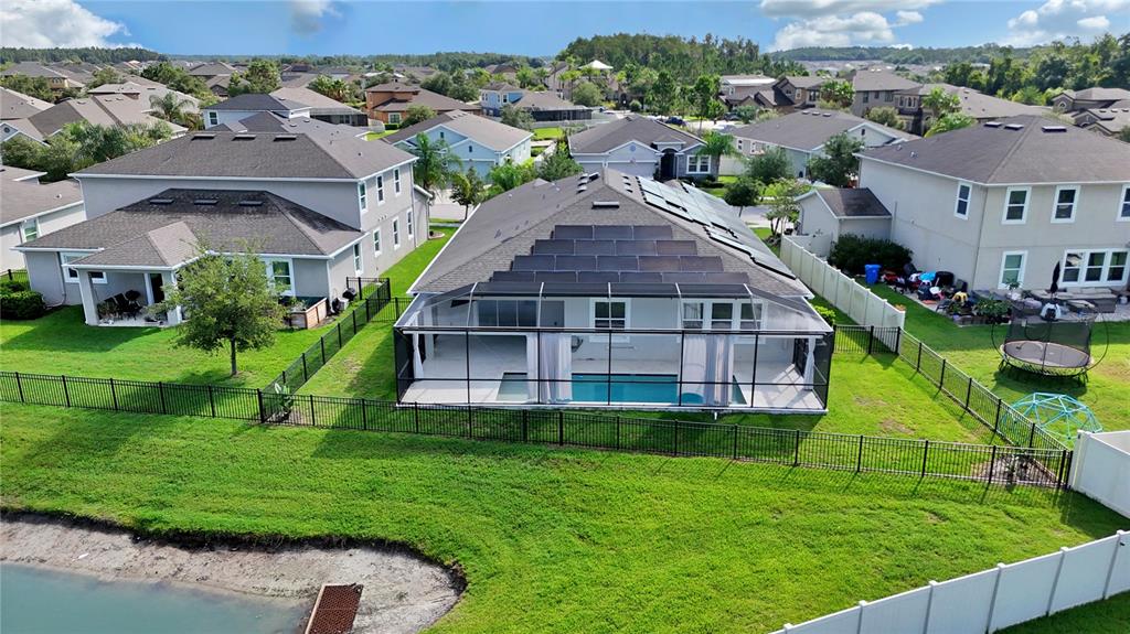 An aerial view of a suburban house with a pool, screened lanai, and solar panels — 32430 BANNACK LANE, WESLEY CHAPEL, FL
