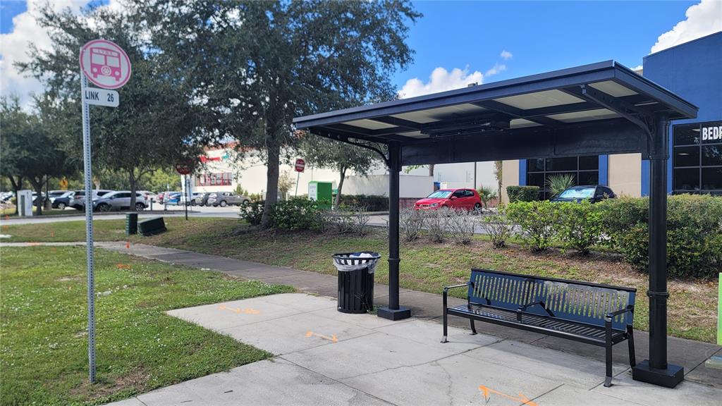 A bus stop with a covered bench, trash can, and a Link 26 route sign — 4476 PLEASANT HILL ROAD, KISSIMMEE, FL