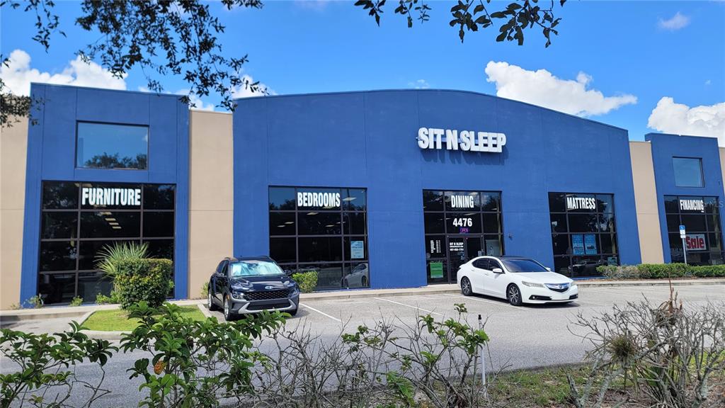 The exterior of a blue commercial building features large windows and signage for a furniture store — 4476 PLEASANT HILL ROAD, KISSIMMEE, FL