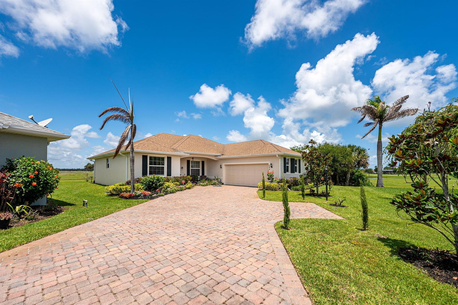 A single-story house with a brick paver driveway, palm trees, and a two-car garage — 598 Gossamer Wing Way, Sebastian FL 32958, SEBASTIAN, FL