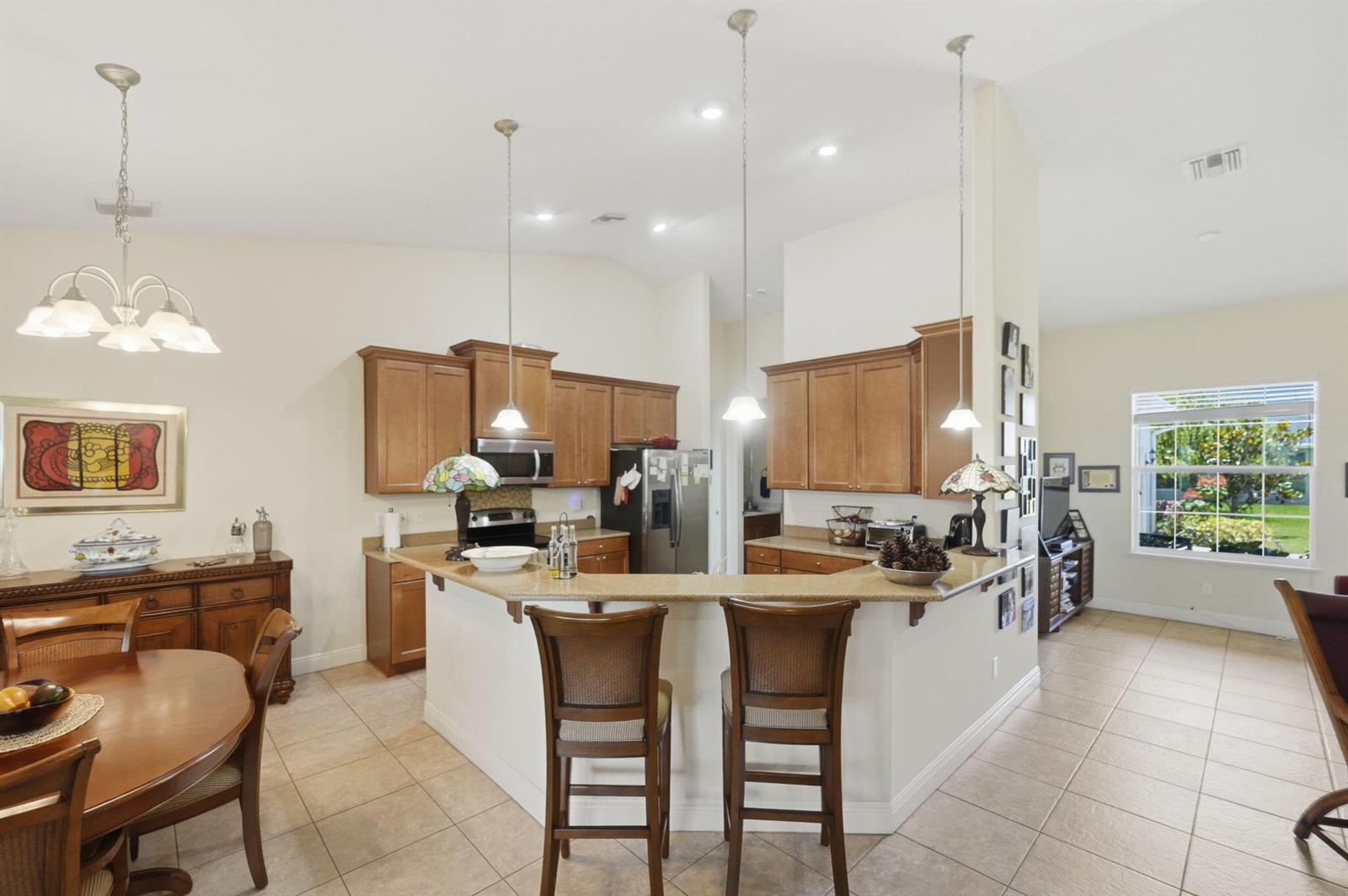 A kitchen with wood cabinets, a breakfast bar, and tile flooring opens to a dining area — 598 Gossamer Wing Way, Sebastian FL 32958, SEBASTIAN, FL