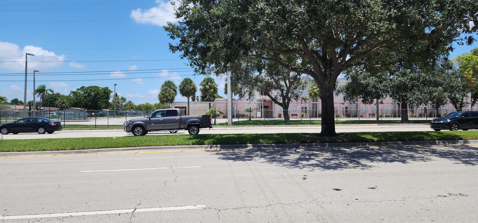 A gray pickup truck drives past a school building behind a chain-link fence — 430 NW 65th Terrace, Margate FL 33063, MARGATE, FL