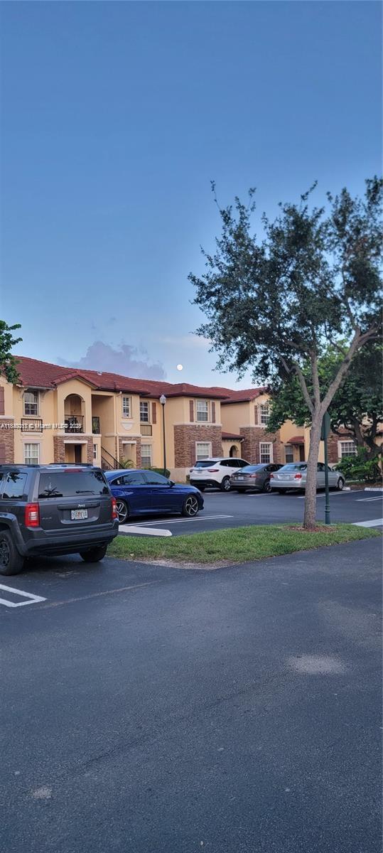 A parking lot sits in front of a two-story apartment building with a tiled roof — 1655 NE 33rd Rd # 4, Homestead FL 33033, HOMESTEAD, FL