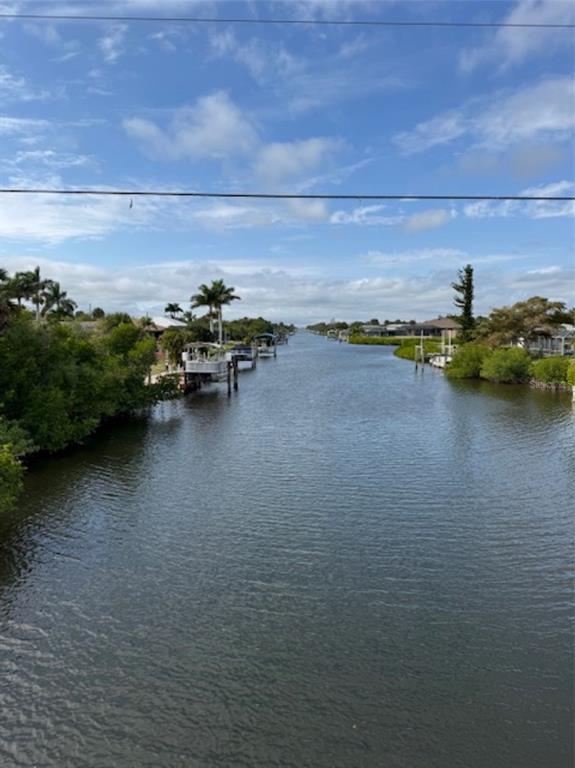 A view of a canal lined with houses, boat docks, and lush green vegetation — 18790 MACGILL AVENUE, PORT CHARLOTTE, FL