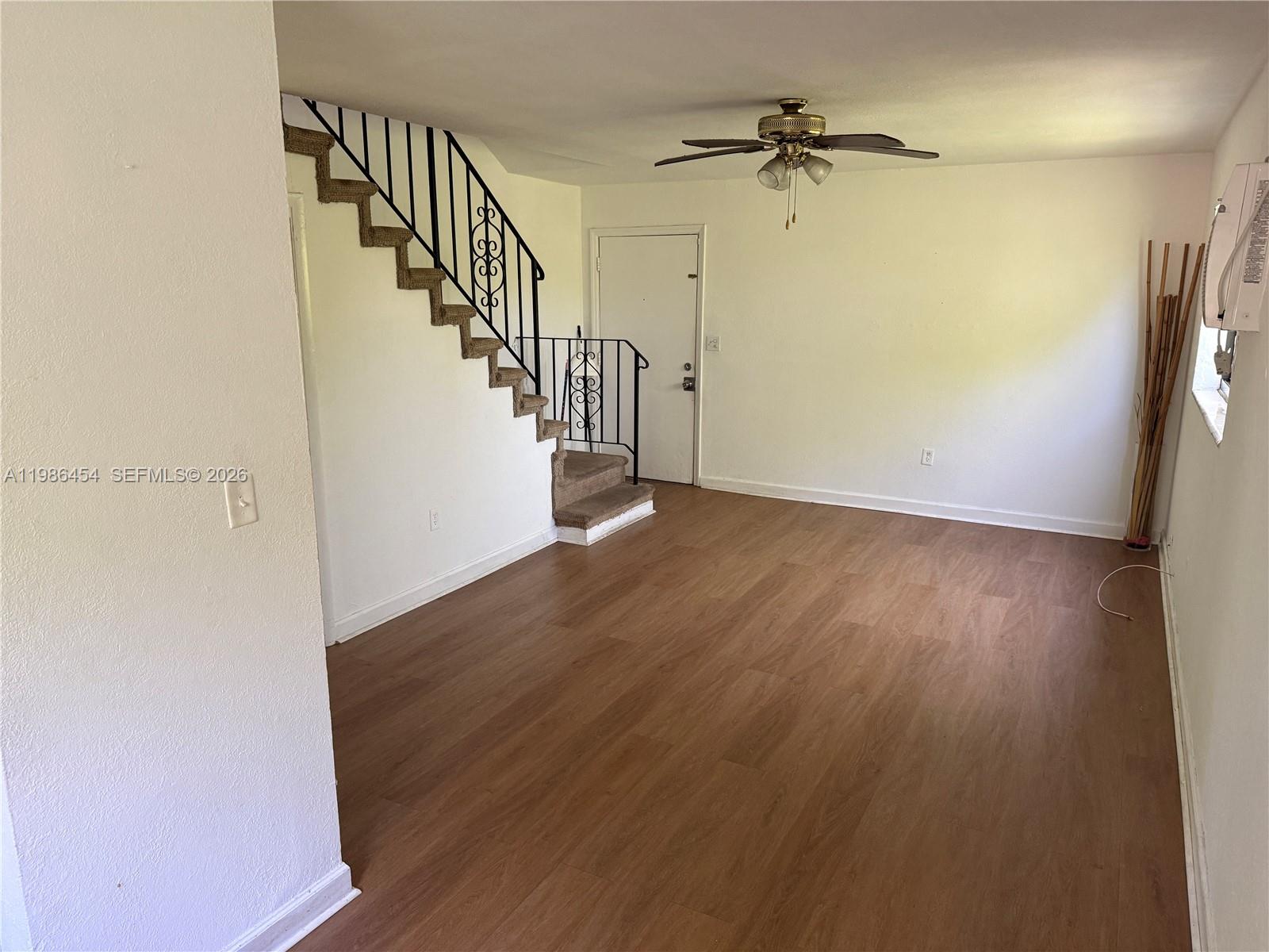 An empty living room features light wood-look flooring, a ceiling fan, and a window air conditioner — 180 NE 71st St # 3, Miami FL 33138, MIAMI, FL